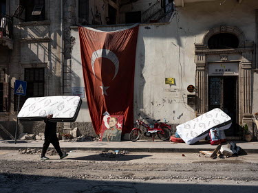 A mosaic portrait of Mustafa Kemal Ataturk leans against a large Turkish flag hanging from a wall on Kurtulus Cadasi in the aftermath of the Monday the 6 February 2023 earthquakes.