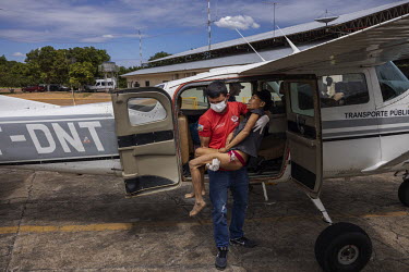 Lina Yanomami, an indigenous woman, from a community in the Surucucu region of the Yanomami Indigenous Territory, suffering from malaria and malnutrition, is carried from a light aircraft by a health...