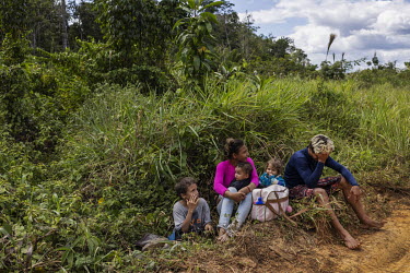 A family that left an illegal mining operation in the Yanomami Indigenous Land waits for transportation on the road that connects a clandestine port on the banks of the Uraricoera River, to the villag...