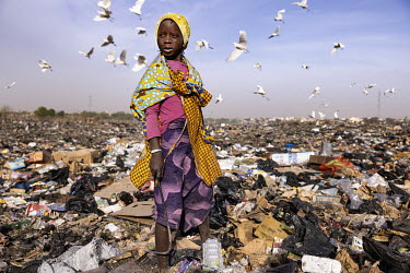 A girl searches through a waste dump looking for anything she can sell to raise money to enable her to survive. She lives in the Faladie camp for displaced persons where 3,600 people are crammed toget...