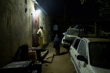 A Fulani night watchman provides security for a garage. Fulani who have moved to the cities often work as guards.