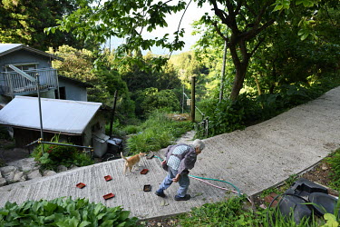 Outside her home in a mountainous hamlet on Shikoku, 91-year-old Toshie Ueno takes a stroll after feeding her 15 cats. She's the last person living in the secluded area. ^I am alone here^, she says, ^...