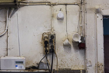 Coffee cups hanging on a wall in a small building in the harbour used by fishermen as a place to bait fishing hooks.