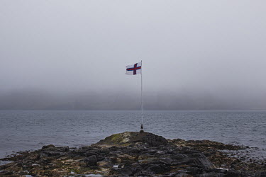 The Faroese flag flies lonely at the water's edge, during the Joannesoka festival.