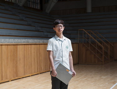 A 14-year-old student holding a laptop at the Shinil High School. Stitched Photograph
