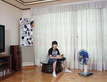 A 12-year-old boy in the living room of his family apartment. Stitched photograph