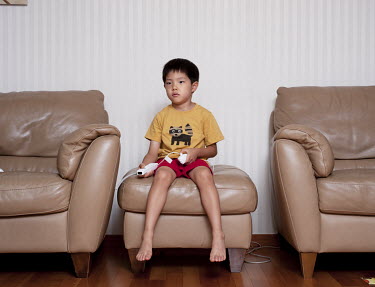 A 6-year-old child playing videogames in the apartment where he lives with his family. Stitched Photograph
