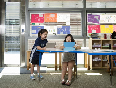 Two 4-year-old children using tablet computers during an English lesson at the Chadwick International School.