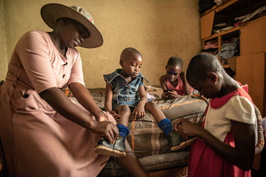 29-year-old Linda Kampira helps her daughter Emilia to take off her foot brace at the family's home. Emilia's mother Linda was initially dissuaded from seeking treatment at a clubfoot clinic due to pr...