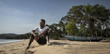 Fisherman Hassan Kargbo (26) sits in front of his boat on Black Johnson Beach, south of Freetown. He used to take home two million Leones per catch, now he is lucky to make 200 and he blames Chinese c...