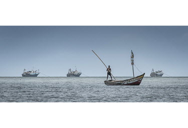 Local fishing boats sail in front of Chinese trawlers sitting at anchor off Tombo Port.