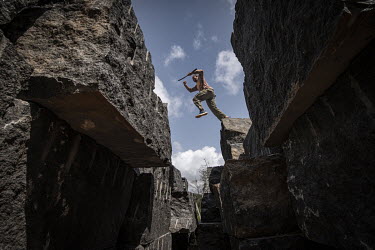 Park ranger Prince Dudbuya leaps across blocks of granite excavated by the Hongtai Company at their quarry in Comfort Bridge in the Western Area National Park.In Sierra Leone, businesses are taking ad...