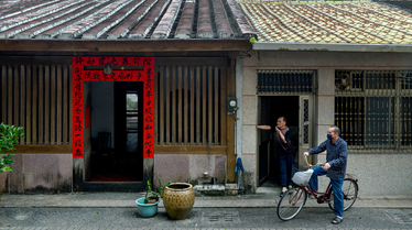 A man rides a bicycle past a former customs warehouse building, the 'Shisanhang' (the thirteen hongs), on Toucheng's Old Street.