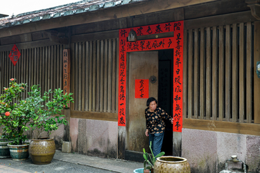 An elderly woman exits a gate in a former customs warehouse building, the 'Shisanhang' (the thirteen hongs), on Toucheng's Old Street.