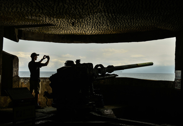 A visitor stands next to a now-decommissioned artillery piece in a former military tunnel complex running through Turtle Island.