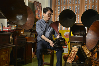 Record collector Dr Hsu Deng-fang speaks into an original Edison recording device while he sits amidst his collection of old gramophones located above his surgery.