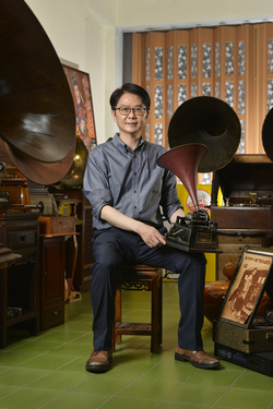 Record collector Dr Hsu Deng-fang with his original Edison recording device while he sits amidst his collection of old gramophones located above his surgery.
