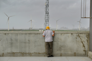 A Taipower employee looks out over a field of massive wind turbines from the rooftop of the Taipower Company's Chang-Yi Switching Station, on Taiwan's windswept west coast.