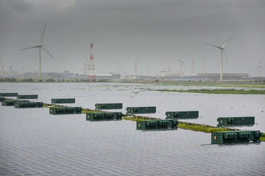 Wind turbines rise above a section of the Taipower Company's massive Changhua Coastal Solar Photovoltaic Field.