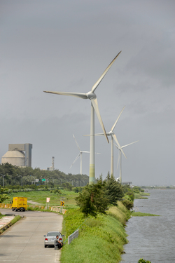 A man fishing in the shadow of massive wind turbines near the Taipower Company's Chang-Yi Switching Station, on Taiwan's windswept west coast.
