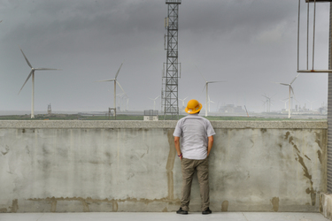 A Taipower employee looks out over a field of massive wind turbines from the rooftop of the Taipower Company's Chang-Yi Switching Station, on Taiwan's windswept west coast.