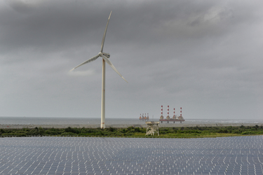 Wind turbines rise above a section of the Taipower Company's massive Changhua Coastal Solar Photovoltaic Field (the platforms at sea are construction bases for future turbine towers).