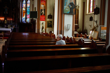 A woman sits alone on a pew in a church after Sunday mass.