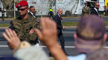 Bodyguards escort Antoni Macierewicz, Vice President of the Law and Justice party, as they walk past a large crowd who have came to watch the largest military parade ever held in post-communist Poland...