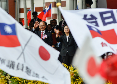 President Tsai Ing-wen (centre, partially covered by flags) waves to members of a Japan/Taiwan friendship organisation who are holding both Japanese and Taiwanese national flags, on Taiwan's 112th Nat...