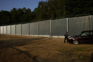 A resident talking to border guards beside the Belarus frontier fence.
