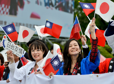 Members of a Taiwan-Japan friendship group wave both the Japanese and Taiwan national flags on Taiwan's 112th National Day.