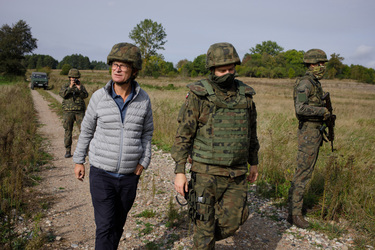 Tomas Lundin, a journalist from the Swedish newspaper Svenska Dagbladet, walks with Polish soldiers who are conducting a patrol along the fence that marks the Belarus border.