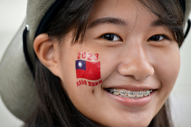 A member of the Girl Scouts, wearing teeth braces and her cheek adorned with a Taiwanese flag sticker, taking part in Taiwan's 112th National Day.