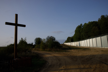 A cross stands beside the frontier fence that marks the border with Belarus.